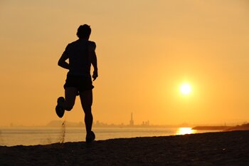 Backlight of a man running on the beach at sunset